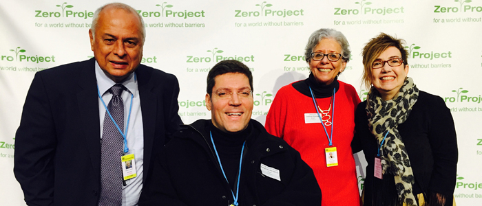 Quatro pessoas posam para foto em frente a banner do Zero Project.