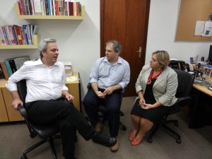 Alexandre Schneider, Augusto Galery e Silvana Drago estão sentados em uma sala conversando sobre o programa Inclui.