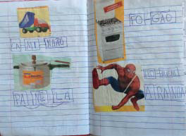 Folha de caderno com imagens de um caminhão, uma panela, um fogão e o homem aranha coladas. Ao lado de cada figura, uma criança escreveu o nome do objeto.