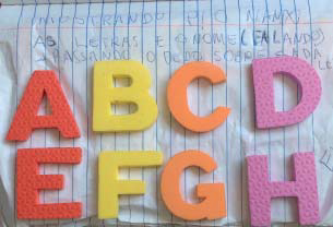 Letras móveis A B C D E F G H sobre uma folha de caderno.