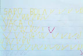 Folha sulfite com palavras como "vaca" e "sapo" escritas por criança com lápis da cor amarela.