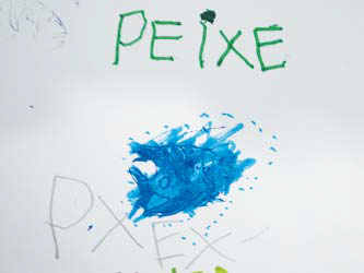 Folha sulfite com escritos e ilustrações de uma criança. É possível ver o desenho de um peixe em azul e a palavra "PXEX" escrita a lápis.