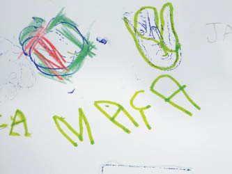 Folha sulfite com escritos e figuras produzidos por uma criança. É possível ler a palavra "Maça" e ver uma ilustração da fruta.