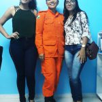 A bombeira Vanisia Sousa Santos posa para foto de uniforme com duas estudantes. As três sorriem. Fim da descrição.