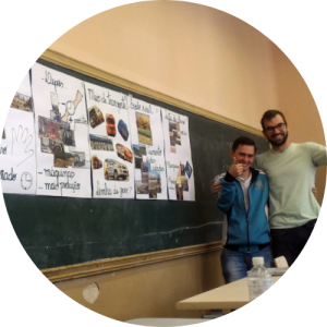 Guilherme e seu professor se abraçam e sorriem para foto ao lado do painel visual com ilustrações sobre a Revolução Industrial preparado pelo estudante. Fim da descrição. 